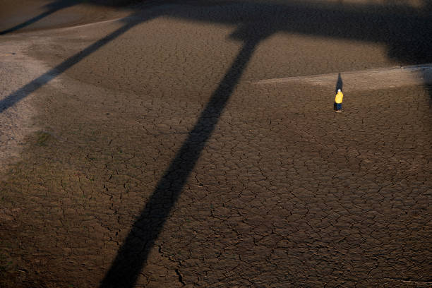 Man stands in a dried-up dam. Drought concept. Climate changes concept. Climate disaster concept.