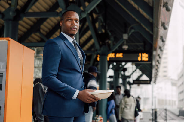 istock Businessman commuting to work, waiting for the train holding his lunch box 2182807075