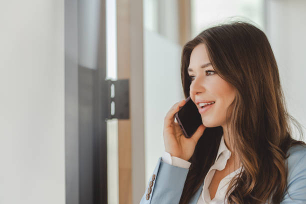 istock Businesswoman smiling while talking on mobile phone in office 2182808786