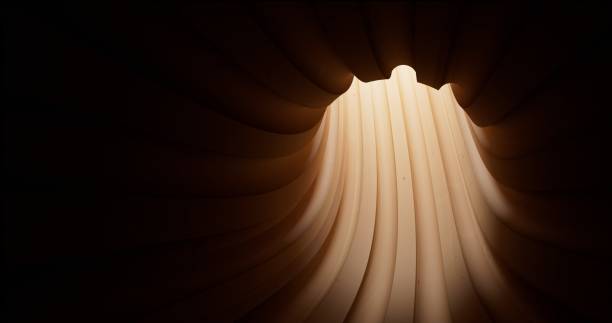 The soft light accentuates a wooden sculpture’s flowing, curved layers, drawing attention to its smooth, organic contours and rich wood texture
