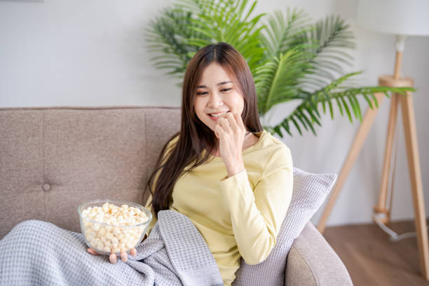 istock Asian woman Watching smart TV and using remote controller Hand holding television audio remote control at home with the remote control television 2182810127