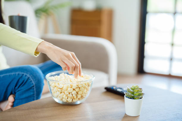 istock Asian woman Watching smart TV and using remote controller Hand holding television audio remote control at home with the remote control television 2182810137