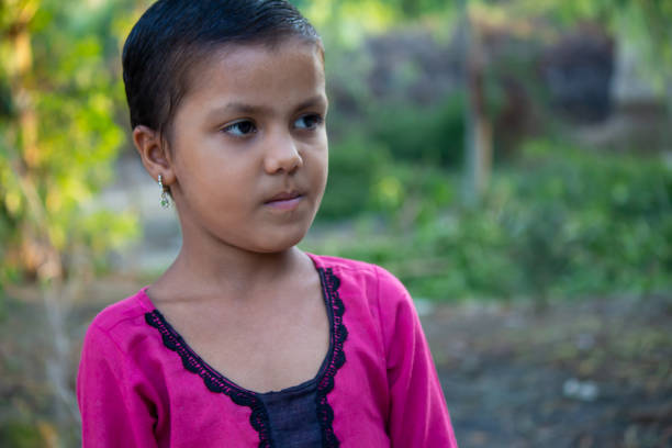 Indian young girl standing outdoors, Her expression is serious and contemplative,