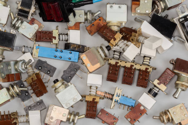Various old outdated electrical switches for switching electrical circuits and power switches of different design on a gray background, fragment top view