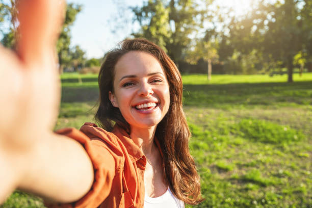 istock Optimistic young woman takes selfie while walking in park after work. 2182813721