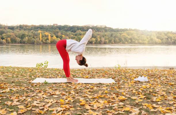 Outdoors workout. Woman practicing yoga stretching exercise by the riverside in nature. Healthy lifestyle.