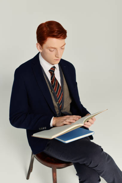 istock Young man with red hair styles a winter outfit in a studio while reading a book 2182815667