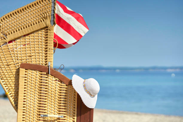 summer hat is hanging on a beach chair at the sea on a summer day