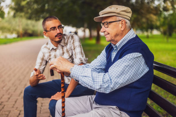 Portrait of grandfather and grandson in park. Old man is worried and concerned but his grandson is consoling him.