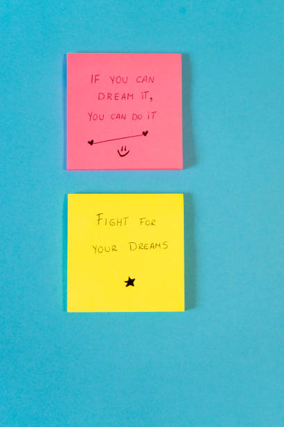 istock Motivational message on a yellow and pink sticky note on a blue background with copy space. 2182818459