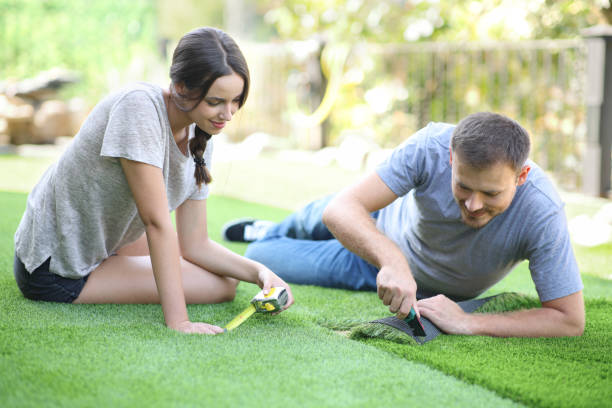 Couple installing artificial turf in their house garden