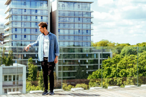 istock Young man on rooftop with urban landscape in background 2182822783