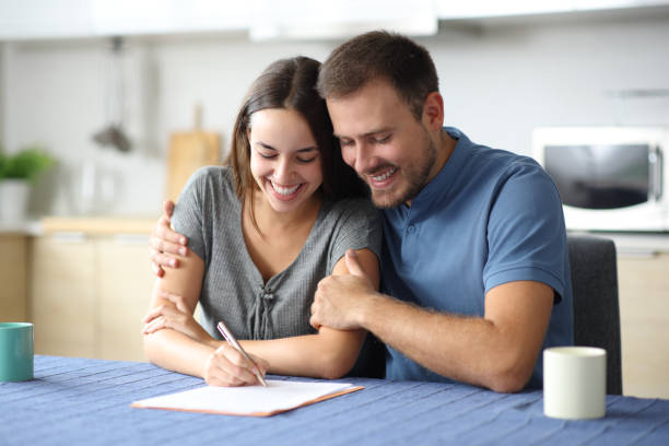 Happy couple signing document at home stock photo