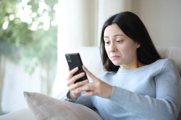 istock Perplexed asian woman checking phone at home 2182823983