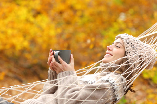 istock Happy woman resting on hammock drinking tea in autumn 2182824246