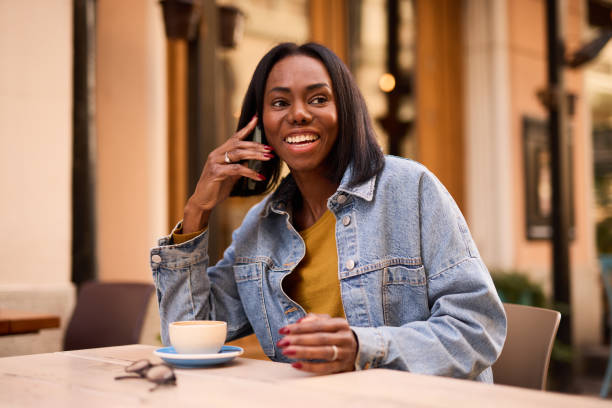 istock Smiling Woman Enjoying Coffee While Using Smartphone Outdoors 2182824401