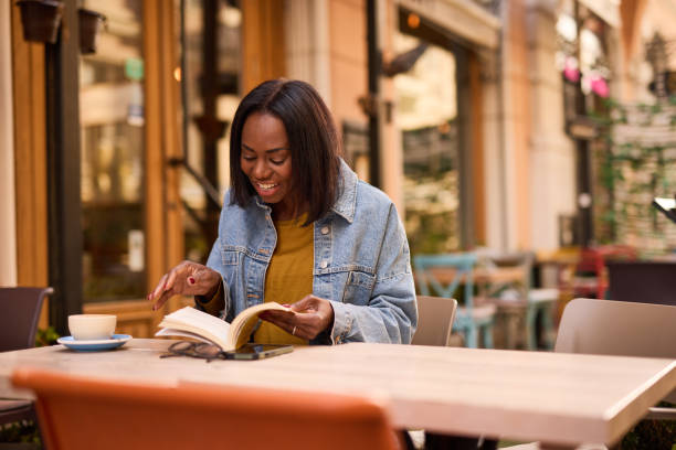 istock Woman is sitting in a cafe and enjoying her coffee while reading a book 2182824423