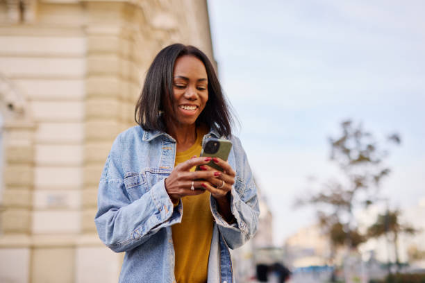 istock Smiling Woman Using Smartphone Outdoors in Urban Setting 2182825282