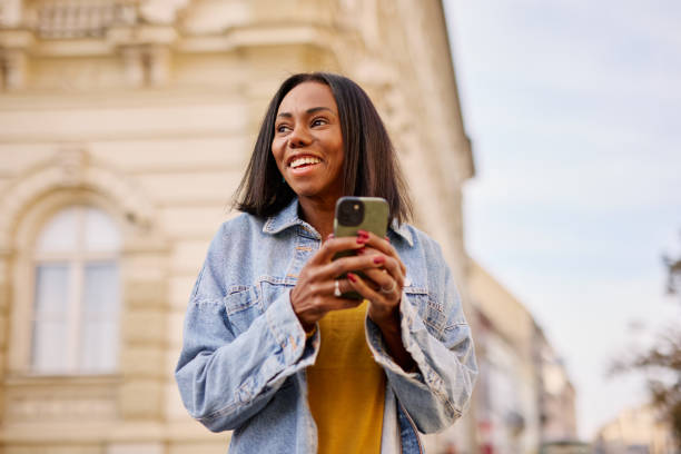 istock Smiling Woman Using Smartphone Outdoors in Urban Setting 2182825306