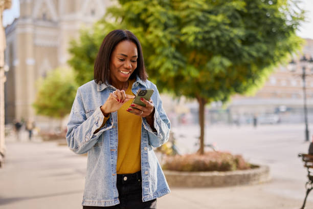 istock Smiling Woman Using Smartphone Outdoors in Urban Setting 2182825337