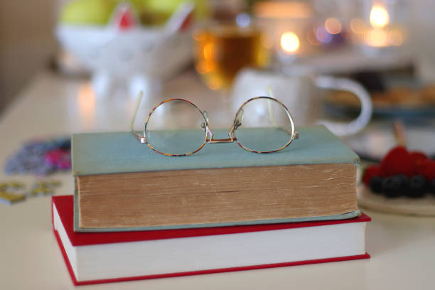 Colorful jigsaw puzzle pieces, books, tablet, glasses, cookies, berries, cup of tea or coffee, glass of juice and lit candles on the table. Hygge in pastel colors. Selective focus.