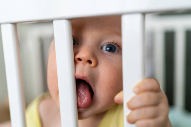 istock Baby boy licking bars from the crib 2182826227