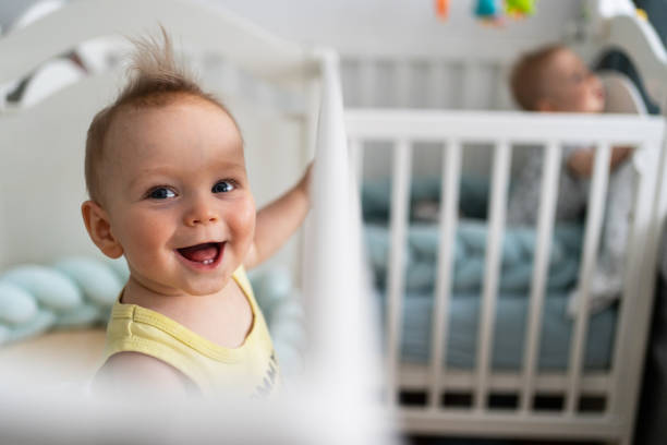 An adorable baby boy smiling happily in his bed in the nursery room