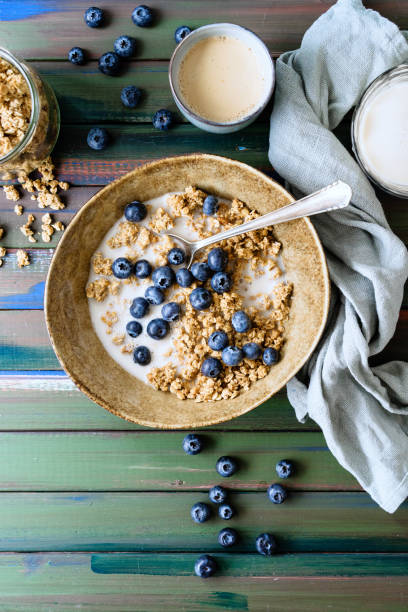 Knuspermüsli mit Heidelbeeren auf einem grünen Holztisch und einer Tasse Kaffee