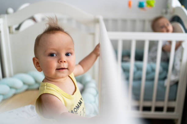 Cute twin baby boys peeking from the crib after waking up in the morning