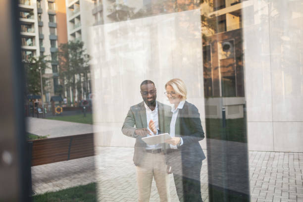 Two business professionals discussing plans outside modern office building