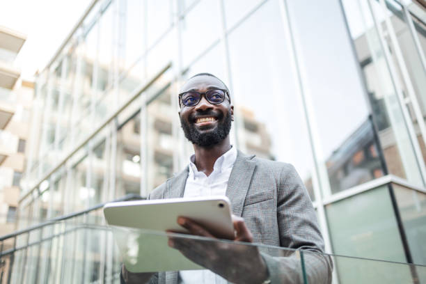 istock Confident businessman holding tablet outside modern office building 2182827905