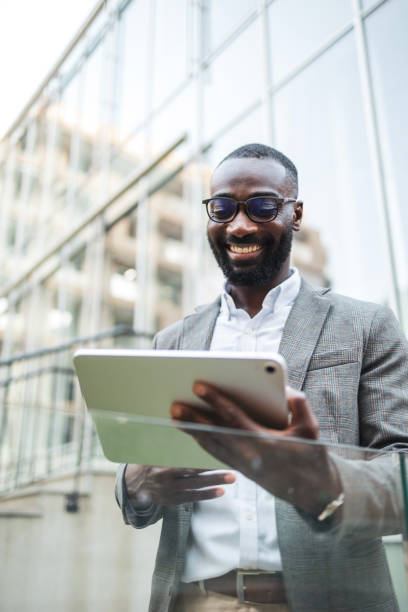 istock Confident businessman using tablet outside modern glass building 2182827910