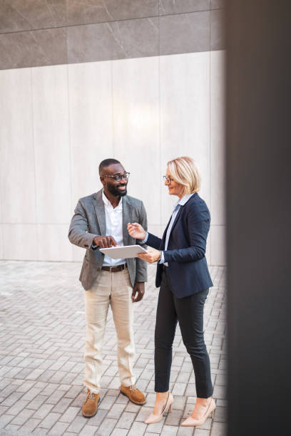 istock Two business professionals discussing project on tablet outdoors 2182827922