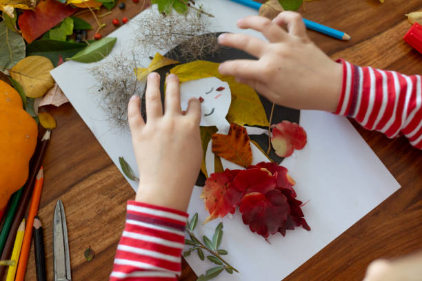 istock Sweet child, boy, applying leaves using glue while doing arts and crafts at home 2182829242