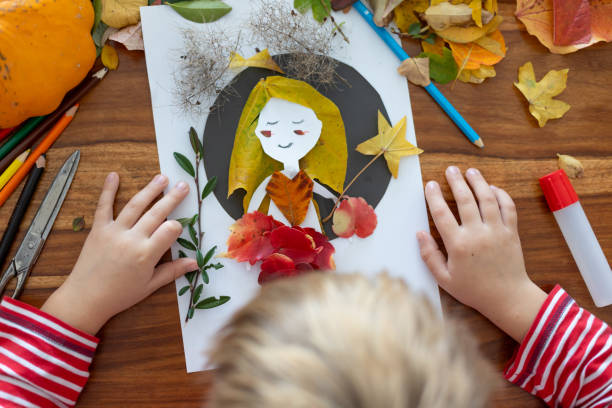 istock Sweet child, boy, applying leaves using glue while doing arts and crafts at home 2182829285