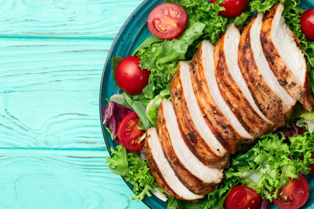 istock Grilled chicken breast ( fillet ) with lattuce salad and cherry tomatoes . Top view 2182832545