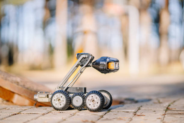 istock A close-up of a small wheeled inspection robot with a camera beside an open manhole, designed for sewer or underground inspection tasks. 2182833366