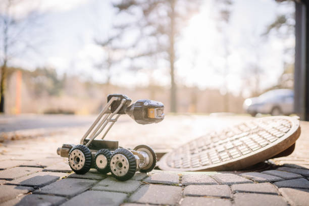 istock A wheeled inspection robot with a camera sits near an open manhole on a cobblestone surface, ready for underground exploration and maintenance tasks. 2182833368