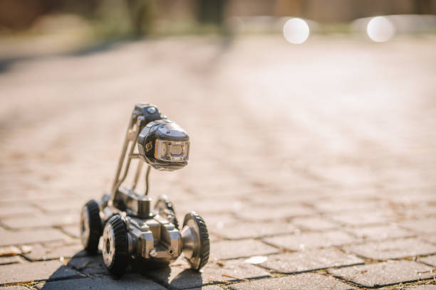 istock A small inspection robot with a mounted camera on wheels positioned on a paved outdoor surface, used for monitoring and maintenance purposes. 2182833410