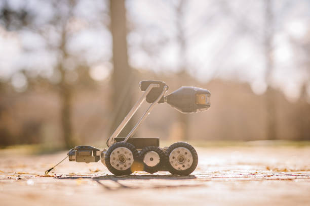 A wheeled inspection robot with a camera, positioned outdoors on sunlit pavement, ideal for infrastructure monitoring and exploration tasks.