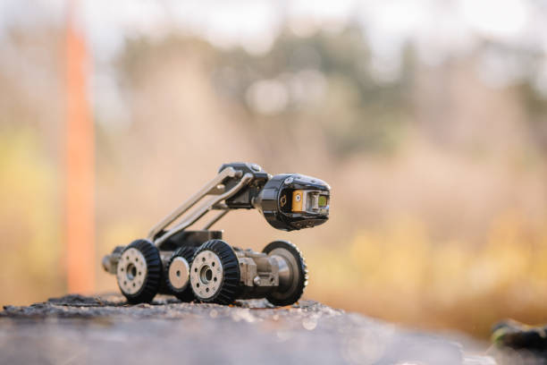 A compact, wheeled inspection robot on a reflective surface, with a blurred natural background, suggesting outdoor exploration and technology.