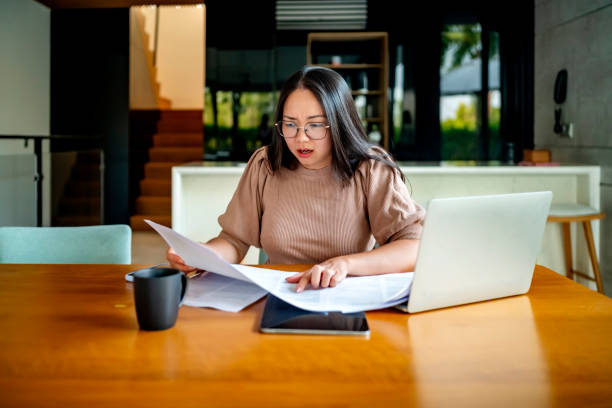 istock Concerned Woman Reviewing Documents at Home Office Desk 2182833955