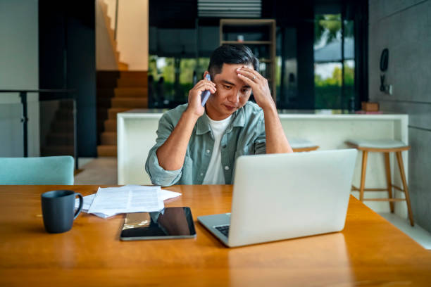 istock Stressed Man on Phone Working at Home Desk with Laptop 2182833968