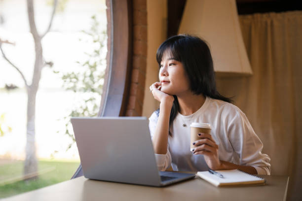 istock Young Asian woman taking a coffee break while working remotely in a coffee shop. 2182834215
