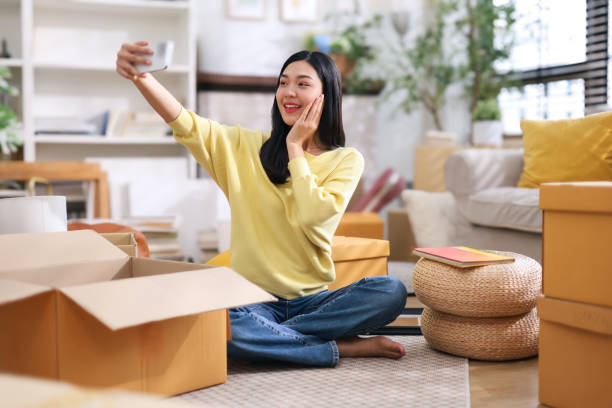 istock Cute young asian woman using her phone to take selfie while preparing to pack products into a box. 2182836652