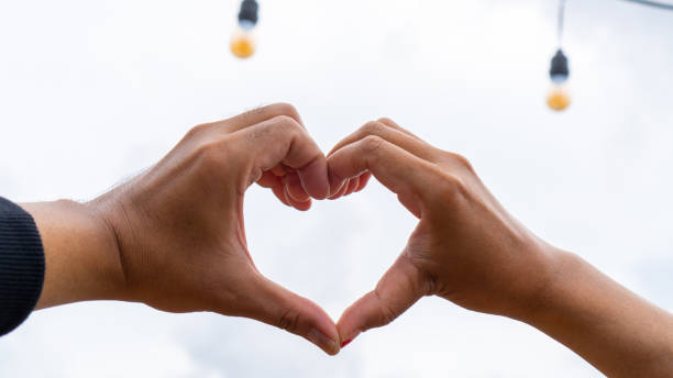 istock Heart symbol hand gesture on a cloudy and evening sky 2182838714