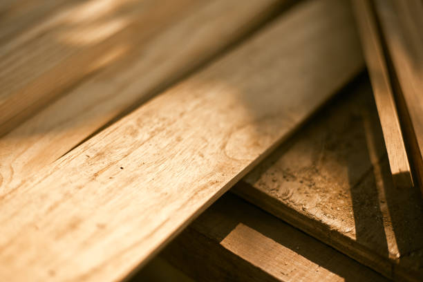 A large stack of lumber boards is neatly stacked at a lumber yard. The boards are arranged in a uniform pattern, with the grain running vertically