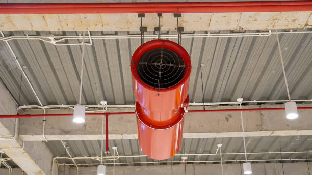 A red impulse jet fan is installed in a room within a building, positioned to efficiently circulate air. The fan's sleek, modern design contrasts with the surrounding interior, adding a functional yet bold element to the space. Its powerful airflow is ideal for ventilation and climate control, ensuring optimal air quality within the room