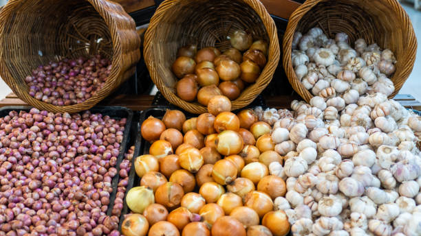 istock Shallots, garlic and onions on display in a supermarket basket window. View from the front 2182840982