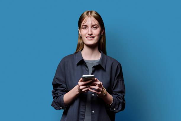 istock Young beautiful woman using smartphone on blue studio background 2182841577